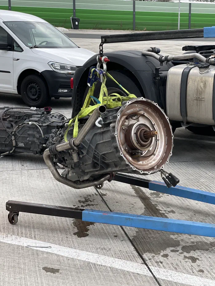 Truck gearbox on an engine hoist during a roadside repair